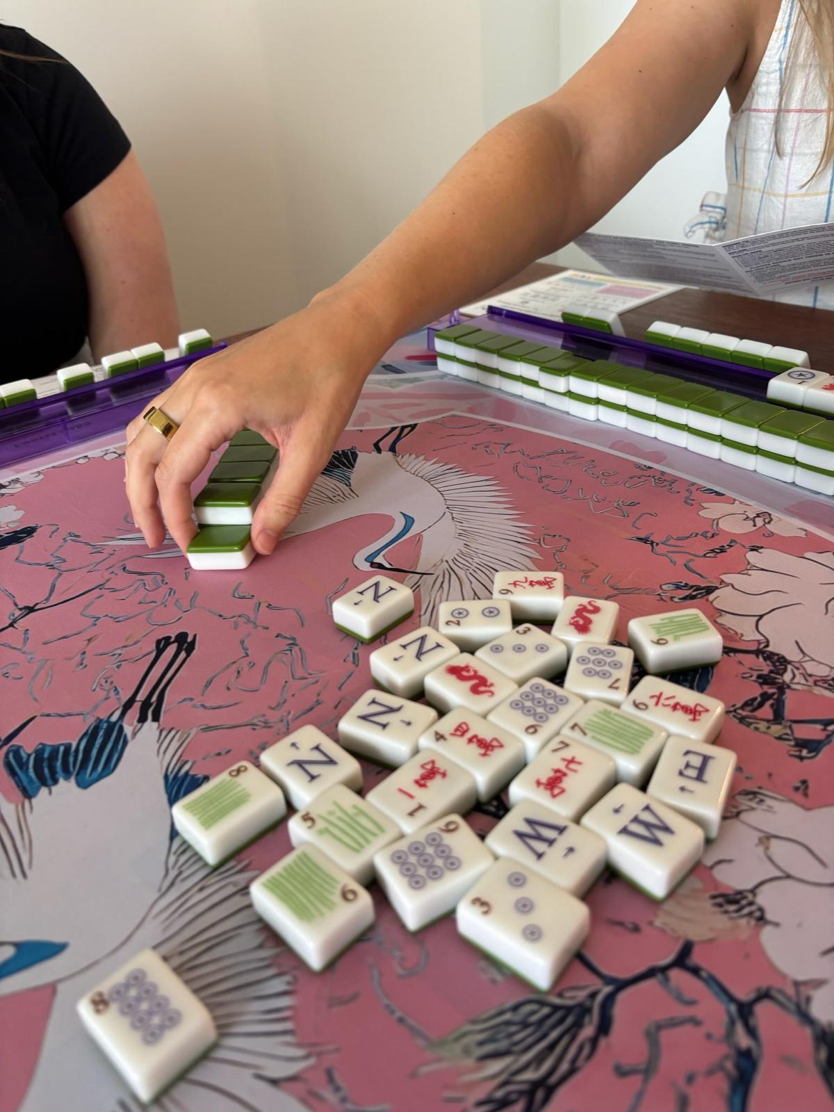 A Mahjong player drawing a tile during a lesson