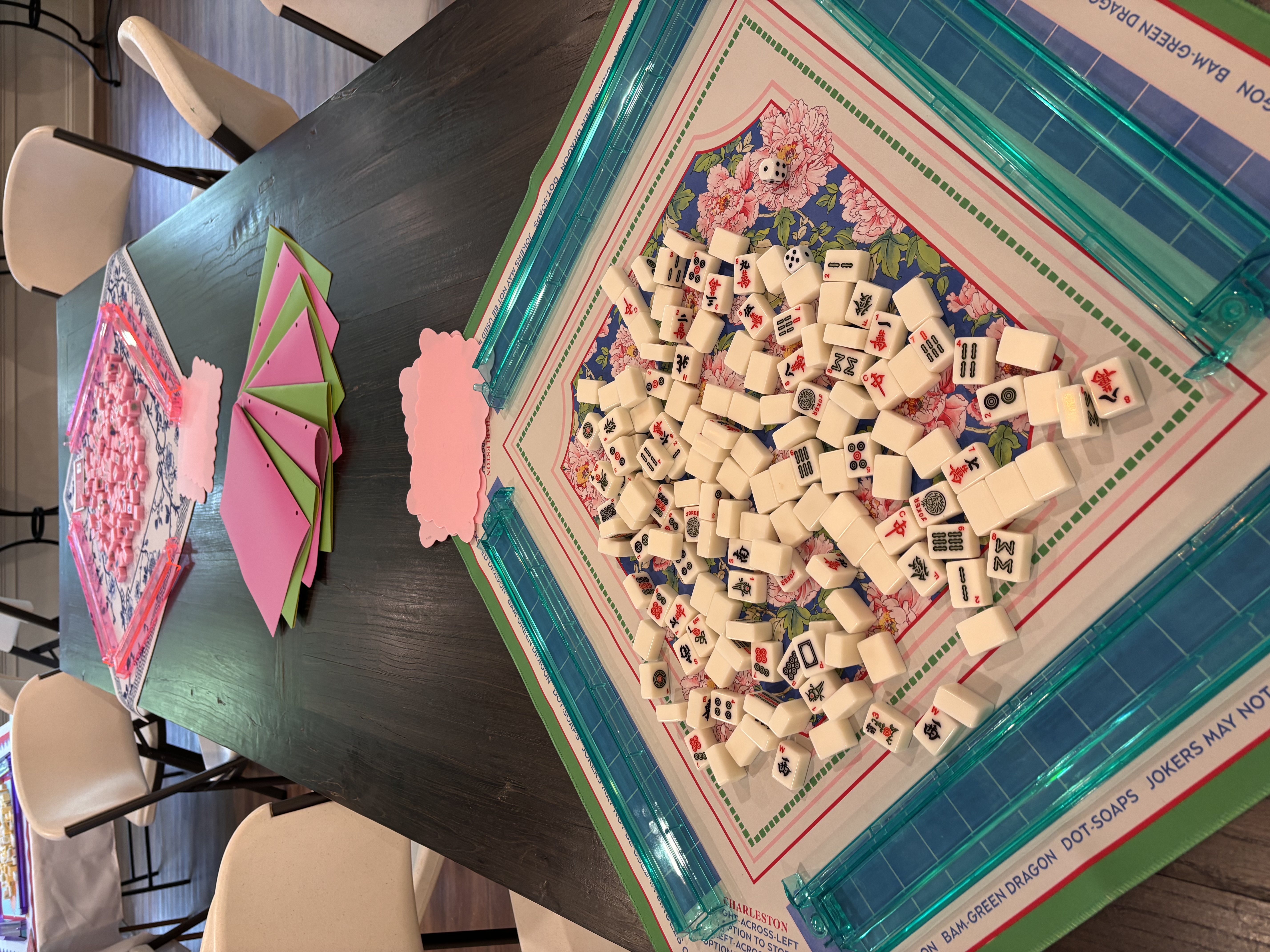 Colorful Mahjong tiles and racks arranged on a floral game mat